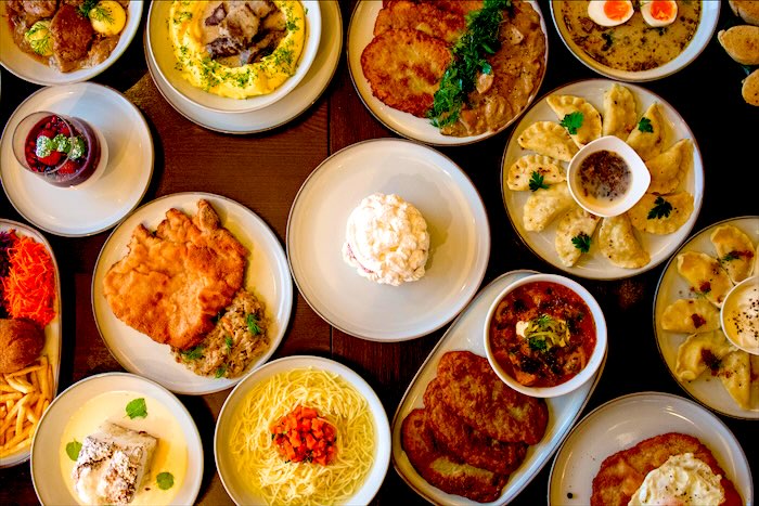 Stół pełen polskich dań: schabowy, pierogi, rosół, placki i żurek