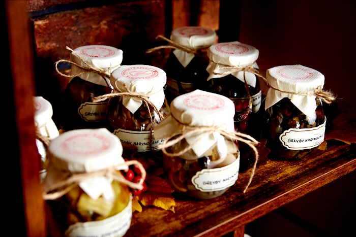 Słoiki marynowanych grzybów z płóciennymi przykrywkami na drewnianej półce